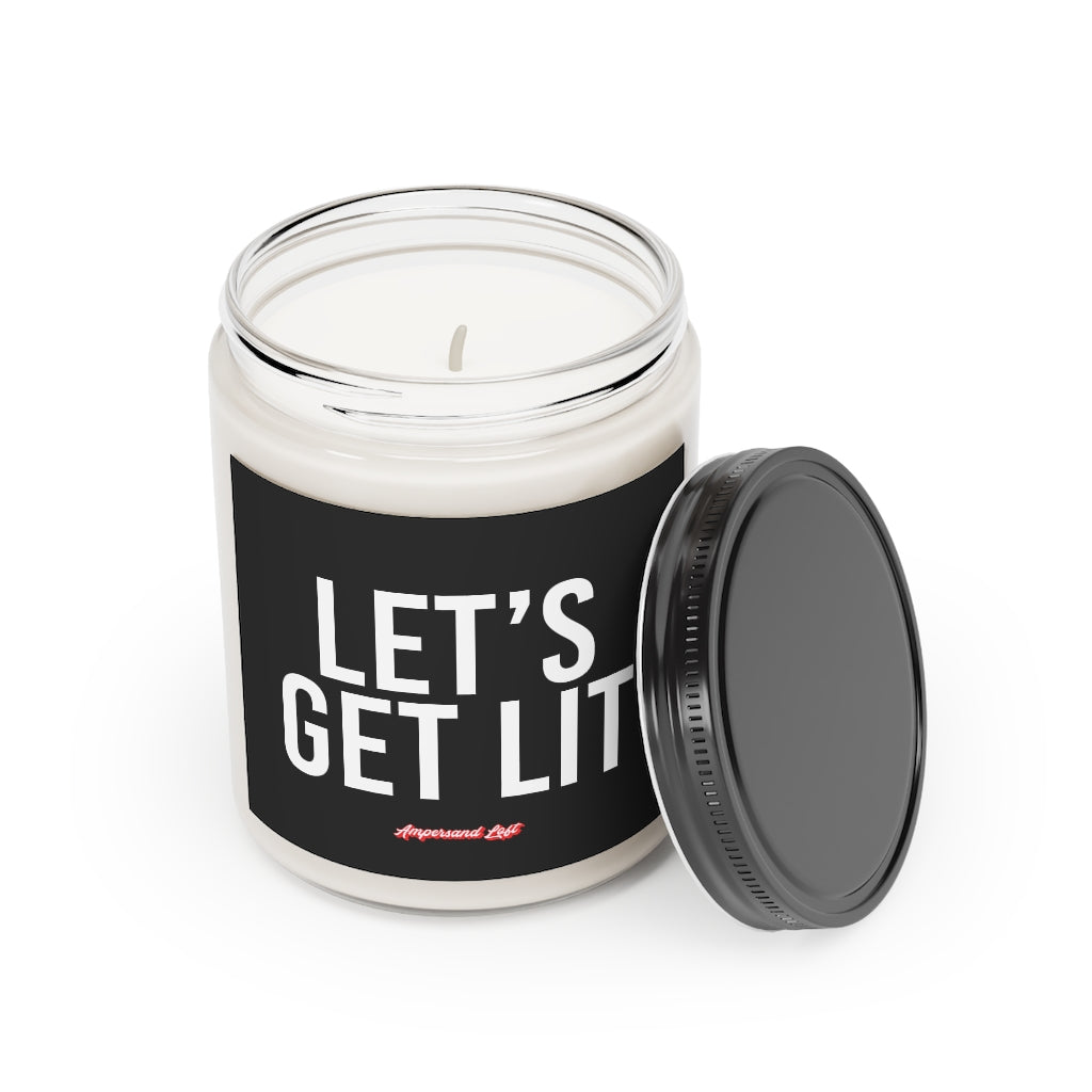 Candle in a glass jar with the lid off, resting on the side of the candle. Black label that reads, in white All-Caps text "Let's Get Lit" and a small "Ampersand Loft logo below (pink retro font with solid red drop shadow)