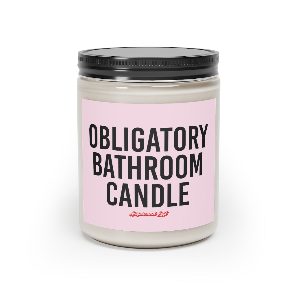 Candle in a glass jar with pink label that reads, in black All-Caps text "Obligatory bathroom candle." and a small "Ampersand Loft logo below (pink retro font with solid red drop shadow)